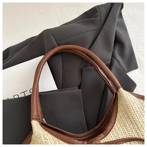 Close-up of the woven straw texture and brown leather handle attachment on a tote bag