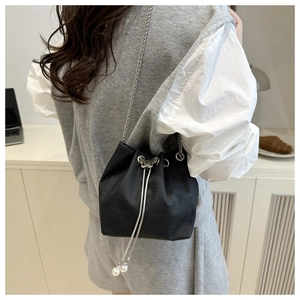 Détail du sac seau noir à cordon avec gaufrage carré et breloque papillon en argent
