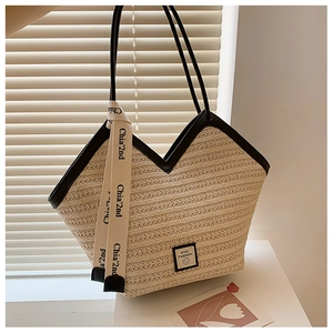 Detail of woven straw tote bag with black leather trim and decorative ribbon accent