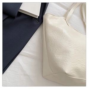 Dettaglio della borsa tote bianco crema con trama in pelle stropicciata e tracolla sottile