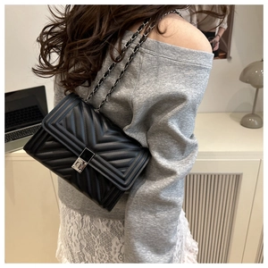 Detailed view of the black chevron quilted leather surface and silver metal clasp