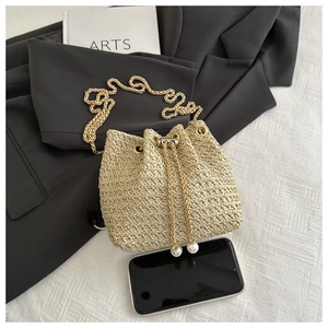 Detail of beige woven straw bucket bag with gold chain and white pearl drawstring accents