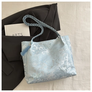Detail of light blue jacquard tote bag featuring 3D butterfly embroidery and braided strap