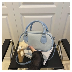 Close-up of light blue lychee pattern bowling bag with cute teddy bear charm and strap