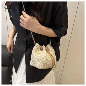 Detail of beige woven bucket bag with elegant pearl drawstring and golden chain strap