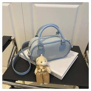 Close-up of light blue textured leather bowling bag with cute plush bear keychain charm