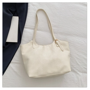 Vista dettagliata di una borsa tote crema con trama fine a pieghe e spalline sottili