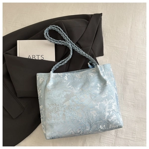 Detail of light blue floral jacquard tote bag with woven handles and elegant embroidery