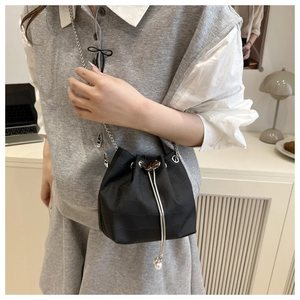 Detail of black crocodile pattern bucket bag with pearl drawstring and silver chain strap