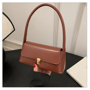 Gros plan d'un sac à main en cuir PU marron avec boucle dorée et texture lisse raffinée