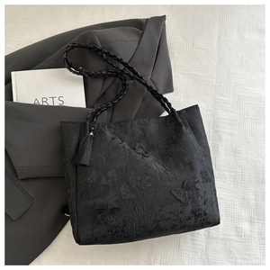 Detail of black lace tote with floral jacquard, 3D butterfly patches and long tassel decor