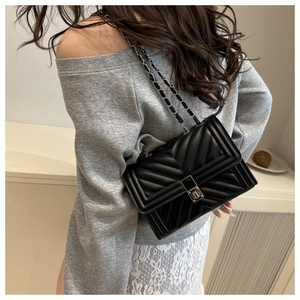 Close-up of black chevron quilted crossbody bag with silver chain strap and metal lock