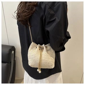 Detail of beige woven bucket bag with pearl drawstring charms and gold chain strap