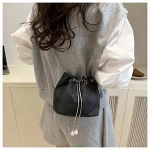 Détail du sac seau noir crocodile avec chaîne argentée et breloques de cordon en perles