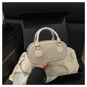 Detailed view of the creamy white lychee grain texture and silver hardware on a crossbody bag