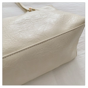 Dettaglio delle cuciture di precisione e finiture dorate sulla borsa tote crema