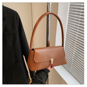 Détail d'un sac porté épaule marron avec fermoir métallique doré et design à rabat épuré