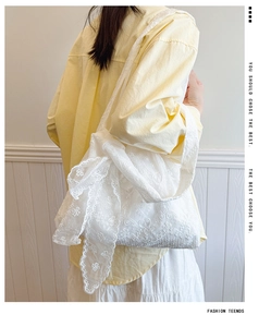 Close-up of white floral embroidery and ribbon bow detail on lace tote bag
