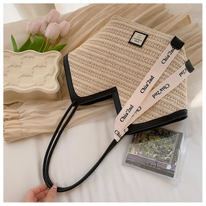 Detail view of woven straw tote bag with black trim and SPORT FASHION patch