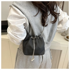 Détail du sac seau noir motif crocodile avec bandoulière chaîne porté par un modèle