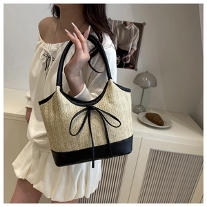 Detail of woven straw tote bag with black leather trim and bow knot in a cozy setting