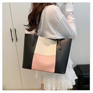 Detail of a geometric tricolor tote bag with black, white, and pink leather panels