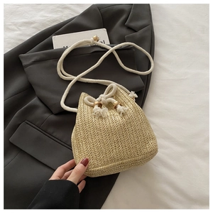Detail der gewebten Strohtasche mit weißem Seilgriff und goldenen Ringmetallbeschlägen