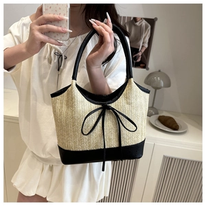 Detail of straw woven tote with black leather trim and bow knot on white clothing
