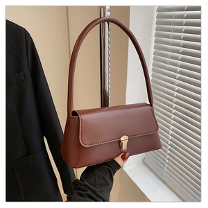 Détail d'un sac à bandoulière marron au fini mat avec fermoir poussoir doré