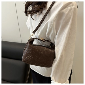 Detailed view of dark brown snake-patterned box bag with adjustable strap and gold buckle