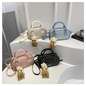 Close-up of four mini Boston bags with litchi texture and cute teddy bear charms