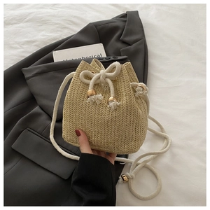 Detail der beigen Beuteltasche mit Fischgrätmuster, weißem Seilriemen und Goldperlen