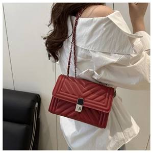 Macro detail of red chevron quilted leather with silver metal lock on a classic bag