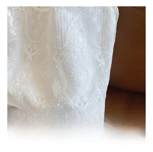 Close-up of white lace floral embroidery on canvas tote bag with intricate hollowed patterns