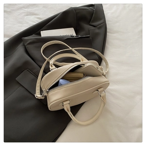 Detail view of cream pebble leather mini bowling bag with silver hardware and interior space