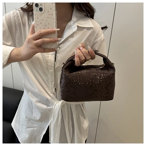 Close-up of small dark brown boston bag with snakeskin texture and metal zipper