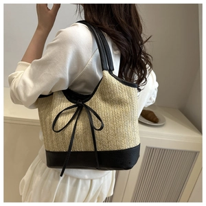 Detail der gewebten Stroh-Tote-Bag mit schwarzem Lederbesatz und Schleife am Model