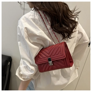 Detail view of red quilted leather chain bag with V-chevron stitching on model