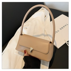 Vue de dessus d'un sac à main en cuir beige avec boucle dorée sur un blazer blanc