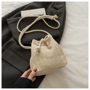 Detail einer beigen geflochtenen Beuteltasche mit Fischgrätmuster und Baumwollkordel