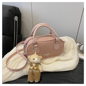 Pink bowling bag with lychee texture featuring dual handles and a plush bear charm