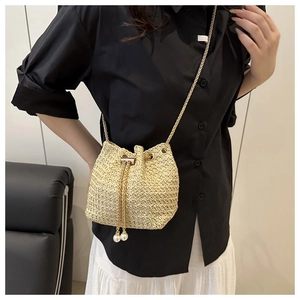 Detail of woven straw bucket bag featuring a drawstring closure and pearl accents