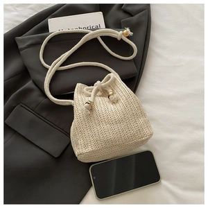 Detail der beigen Stroh-Beuteltasche mit Fischgrätmuster und weißem Kordelriemen
