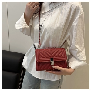 Détail du sac bandoulière matelassé rouge avec fermoir métallique et bandoulière chaîne