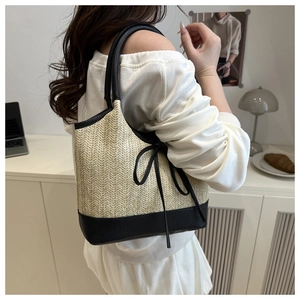 Detail of herringbone weave texture and black faux leather bow on straw tote bag