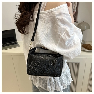 Detail of black python texture leather handbag with adjustable strap and gold hardware
