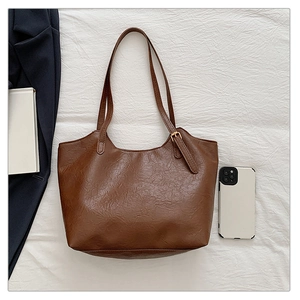 Dettaglio di una borsa tote in pelle PU marrone con trama vintage e spalline sottili