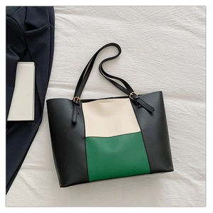Detail shot of tricolor leather tote bag with gold metal buckles on white textured fabric