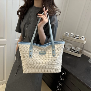 Summer woven tote bag in cream lace with blue leather handles and a metal logo plate