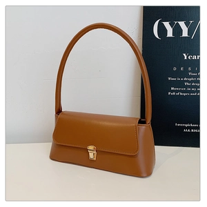 Détail du sac à bandoulière en cuir caramel avec texture fine et boucle en métal doré